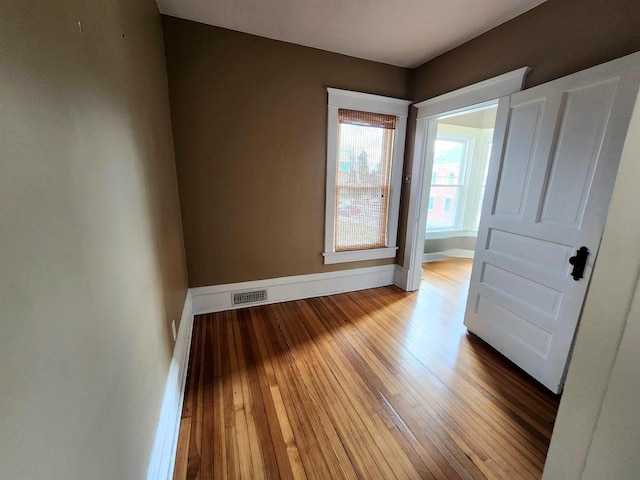 empty room with visible vents, baseboards, and hardwood / wood-style flooring