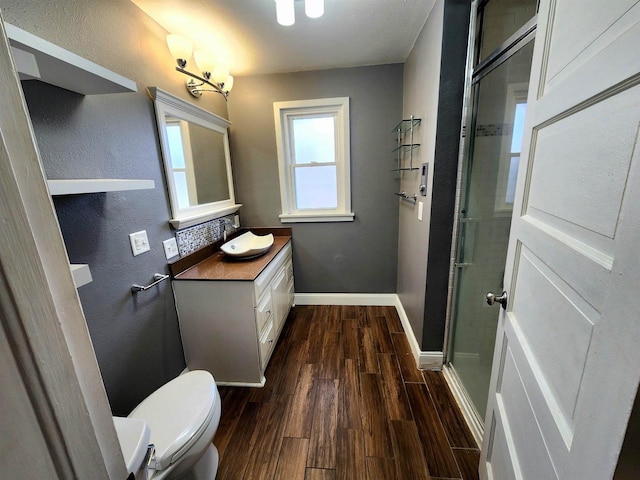 full bathroom with toilet, wood finished floors, a shower stall, baseboards, and vanity