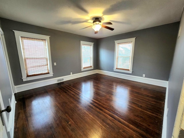 unfurnished room with visible vents, baseboards, wood finished floors, and a ceiling fan