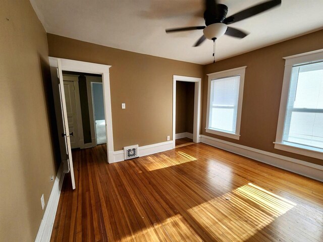 unfurnished room with wood finished floors, visible vents, and baseboards