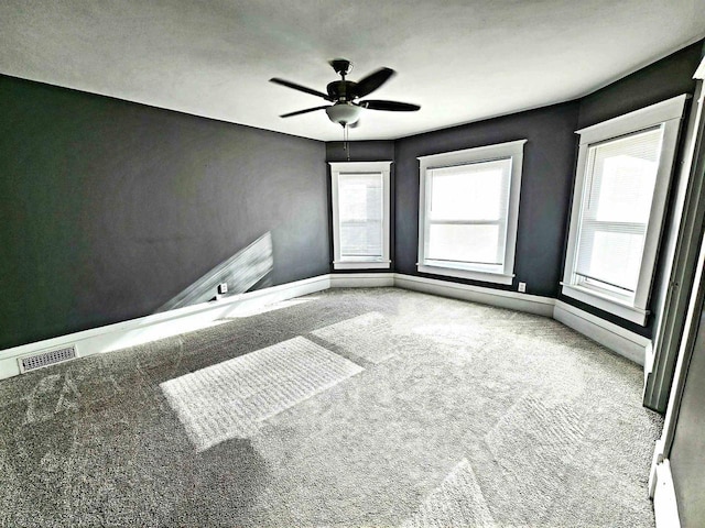 unfurnished room featuring ceiling fan, carpet, visible vents, and baseboards