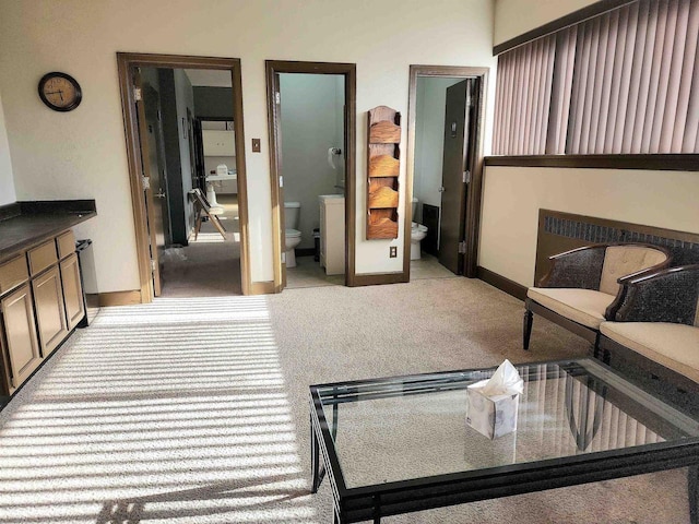 interior space with connected bathroom, baseboards, and light colored carpet