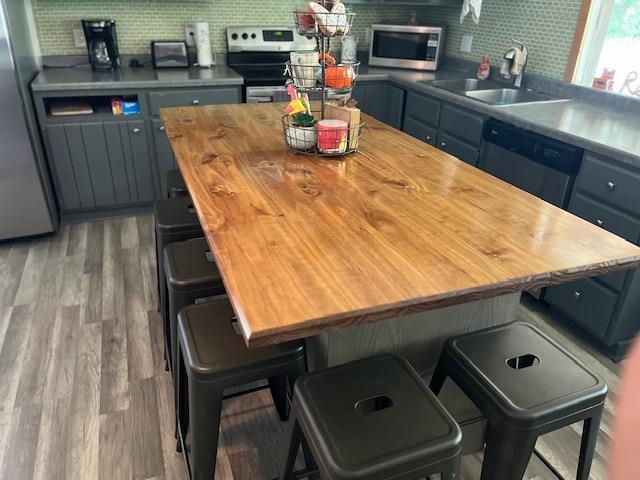 kitchen featuring stainless steel appliances, decorative backsplash, hardwood / wood-style floors, sink, and a breakfast bar