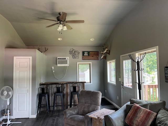 living room featuring ceiling fan, lofted ceiling, dark hardwood / wood-style floors, and a wall unit AC