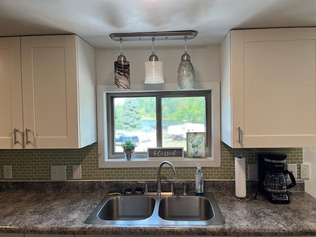 kitchen featuring sink, white cabinets, and backsplash