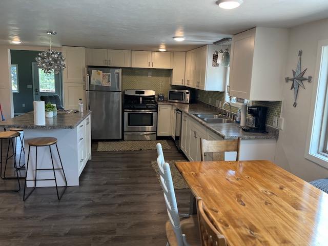 kitchen with stainless steel appliances, dark hardwood / wood-style floors, tasteful backsplash, sink, and white cabinets