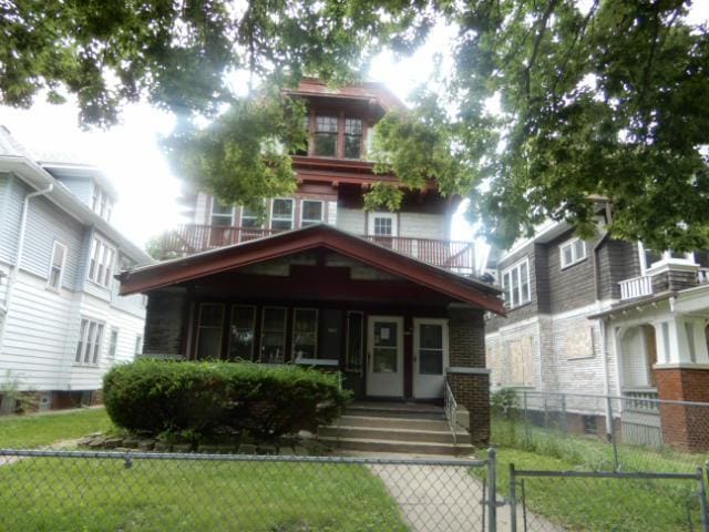 american foursquare style home with brick siding, fence, and a front lawn