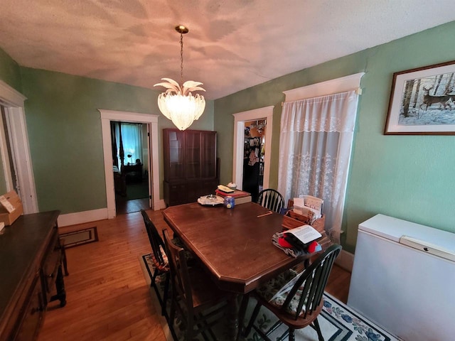 dining area featuring wood-type flooring and an inviting chandelier