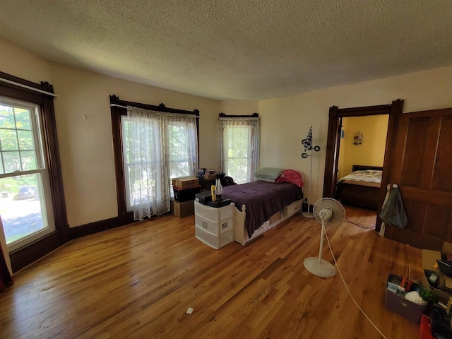 bedroom featuring a textured ceiling, hardwood / wood-style floors, and a barn door