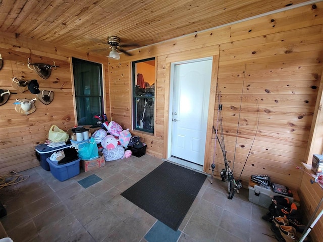 interior space with ceiling fan, wooden walls, wood ceiling, and tile patterned flooring