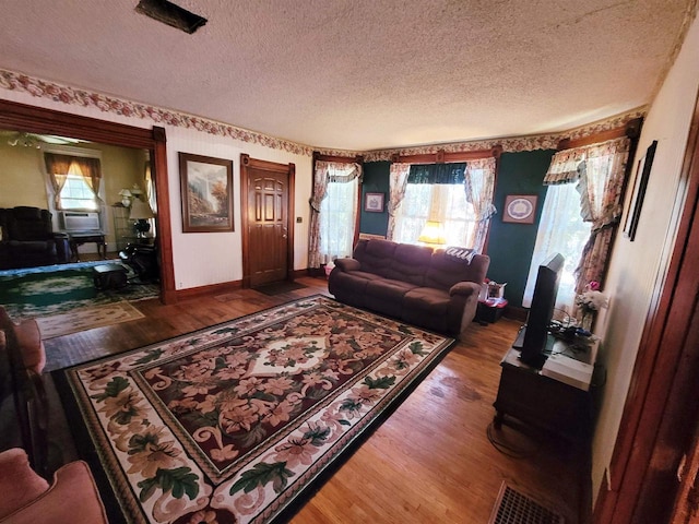 living room with hardwood / wood-style flooring, a textured ceiling, and a wealth of natural light