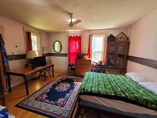 bedroom with ceiling fan, a textured ceiling, and wood-type flooring