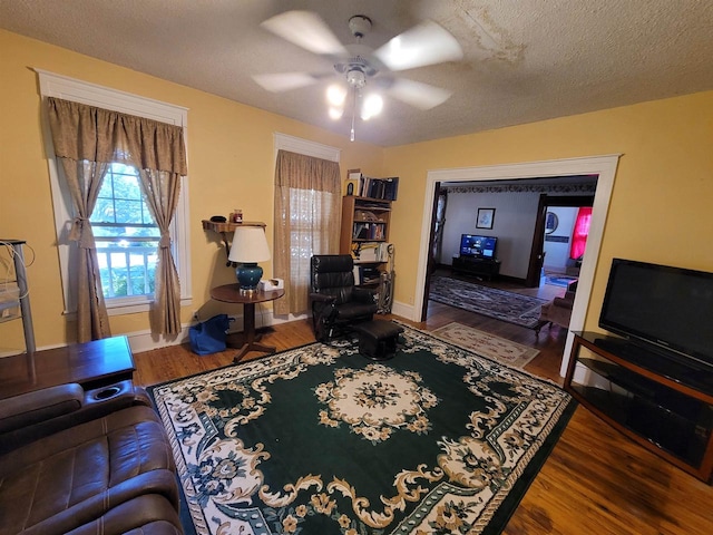 living room with ceiling fan, a textured ceiling, and wood-type flooring