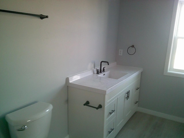 bathroom featuring toilet, baseboards, and vanity