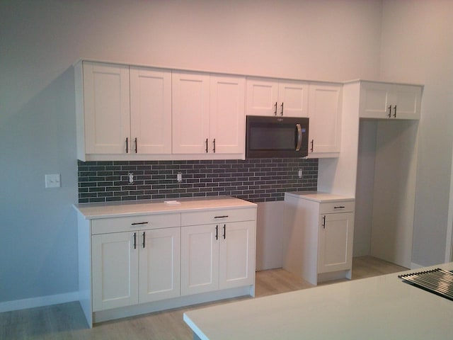 kitchen featuring light countertops, light wood-style floors, backsplash, and white cabinets