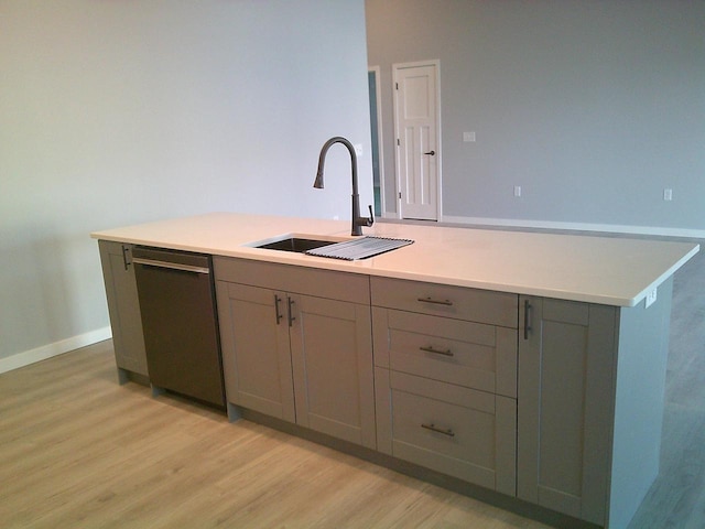 kitchen featuring light wood-style flooring, a sink, baseboards, light countertops, and dishwasher