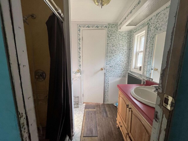N9185 9th Ave, New Lisbon, WI 53950 - bathroom featuring a shower, vanity, wallpapered walls, and wood finished floors