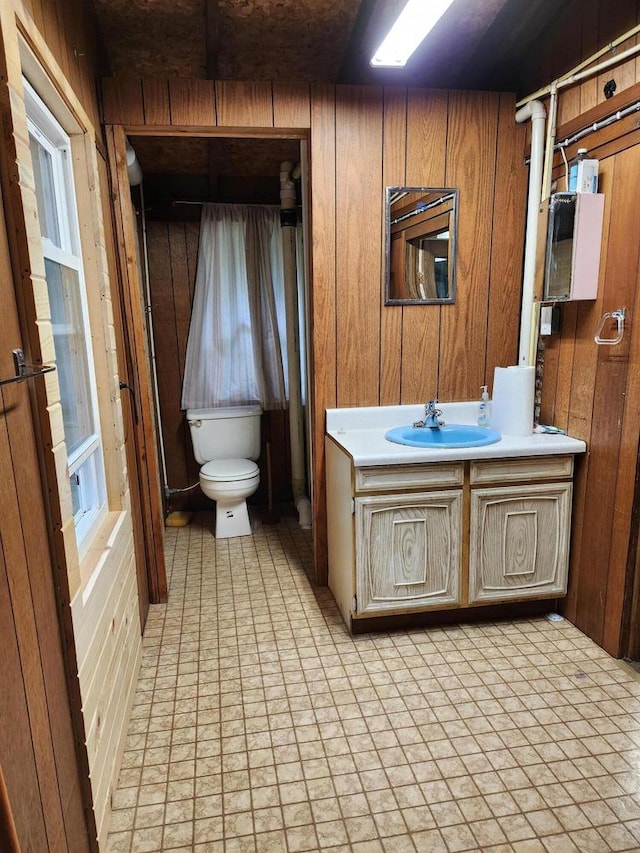 bathroom with tile patterned floors, wooden walls, vanity, and toilet