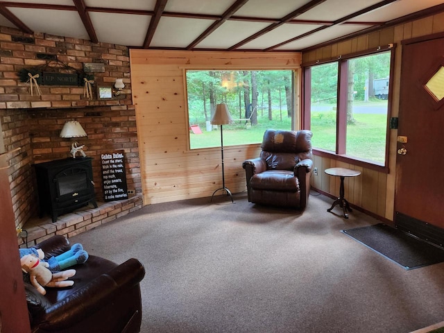 carpeted living room featuring wood walls, beamed ceiling, and a wood stove