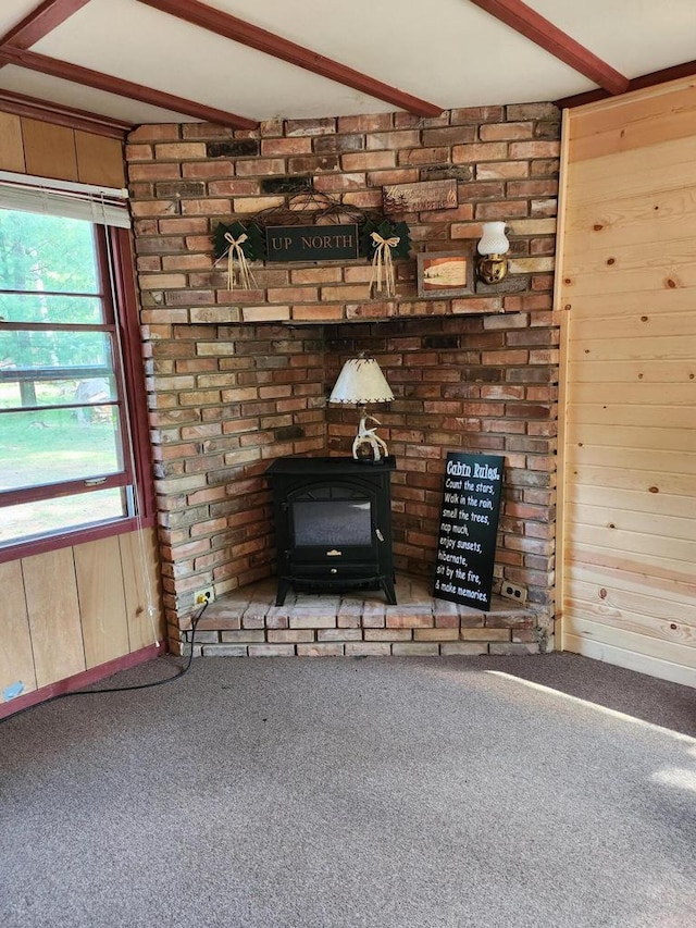 details with beam ceiling, carpet floors, and a wood stove