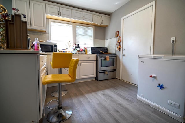 kitchen featuring light wood-type flooring, white cabinetry, decorative backsplash, and stainless steel appliances