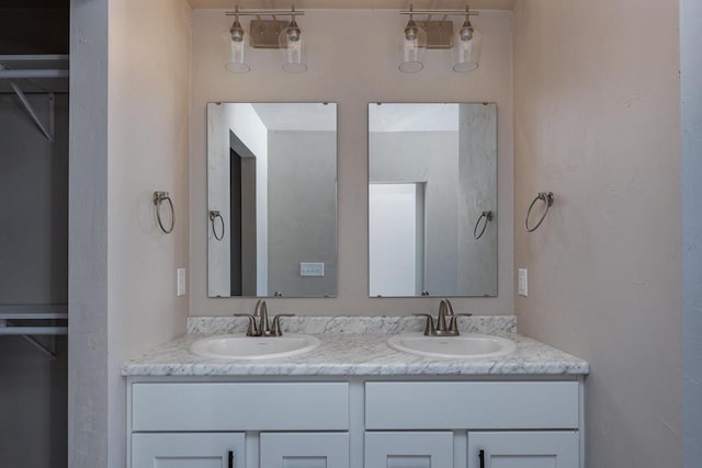 bathroom with a sink, a spacious closet, and double vanity