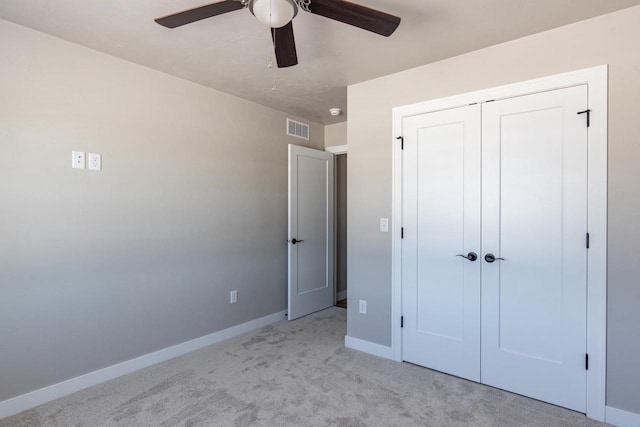 unfurnished bedroom featuring ceiling fan, light colored carpet, visible vents, baseboards, and a closet