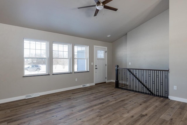 empty room with lofted ceiling, baseboards, visible vents, and wood finished floors