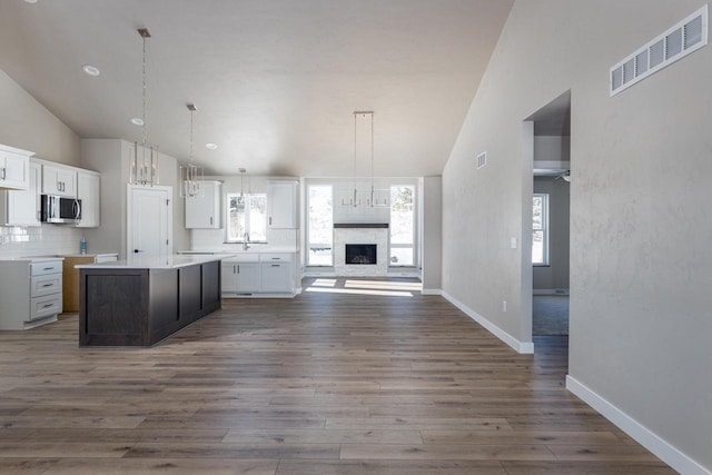 kitchen with open floor plan, light countertops, stainless steel microwave, and white cabinets