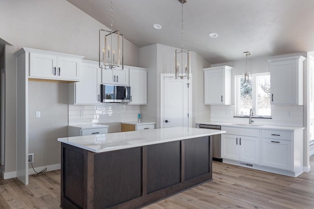 kitchen featuring stainless steel appliances, white cabinetry, a kitchen island, and decorative light fixtures