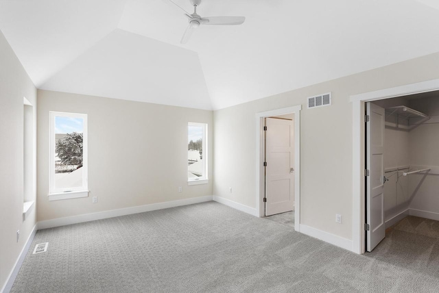 unfurnished bedroom with light carpet, visible vents, a spacious closet, and lofted ceiling