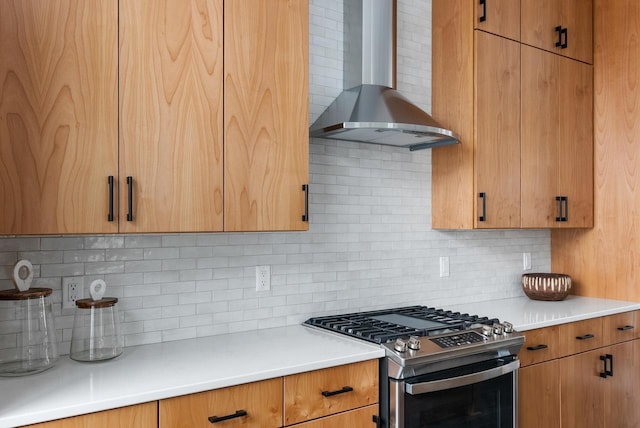 kitchen featuring tasteful backsplash, stainless steel gas range, light countertops, and wall chimney range hood