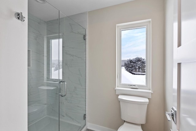 bathroom with baseboards, toilet, and a shower stall