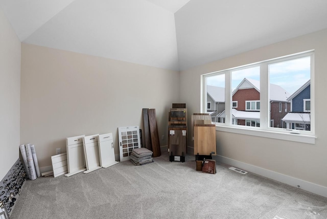 interior space with lofted ceiling, carpet flooring, baseboards, and visible vents