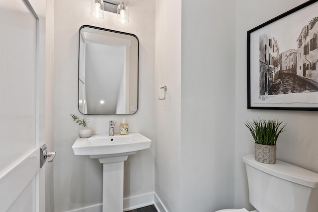 half bathroom featuring baseboards and toilet