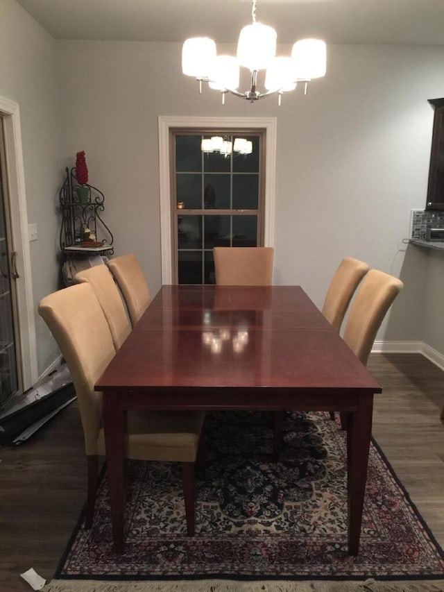 dining room with dark hardwood / wood-style floors and an inviting chandelier