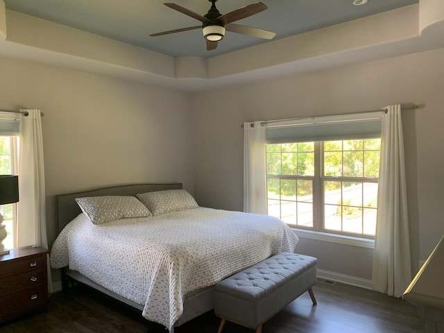 bedroom featuring ceiling fan, dark hardwood / wood-style floors, and a raised ceiling