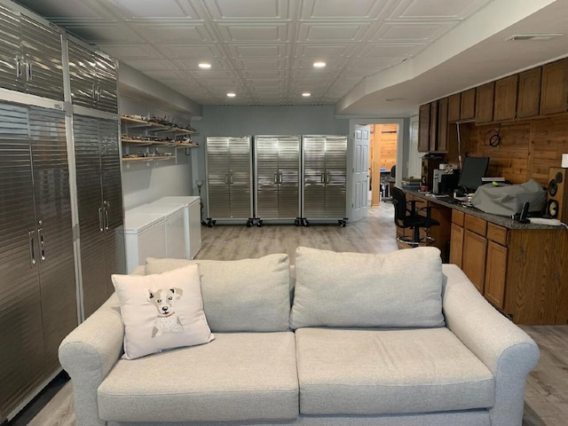 living room with washer and clothes dryer and light wood-type flooring