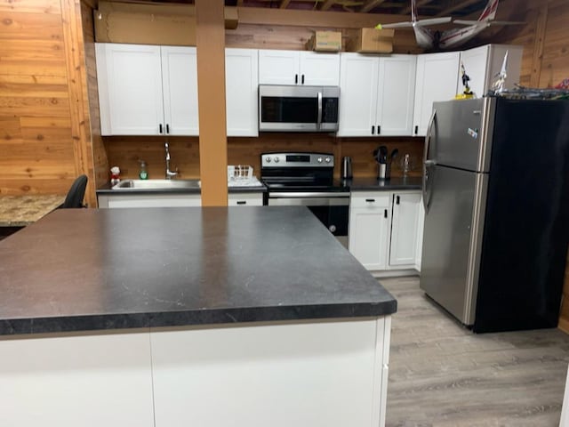 kitchen with stainless steel appliances, sink, light wood-type flooring, and white cabinetry