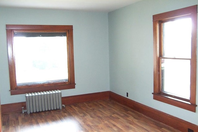 spare room featuring plenty of natural light, dark hardwood / wood-style floors, and radiator heating unit