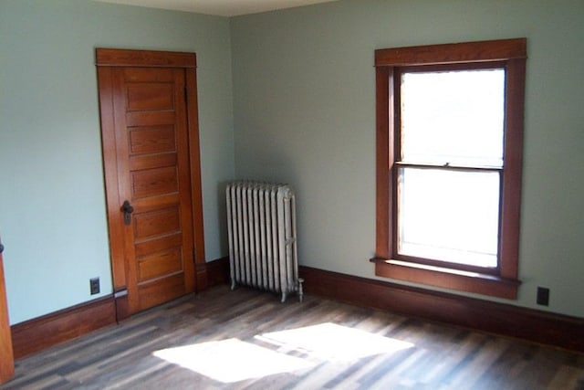 unfurnished room featuring radiator heating unit and dark hardwood / wood-style flooring