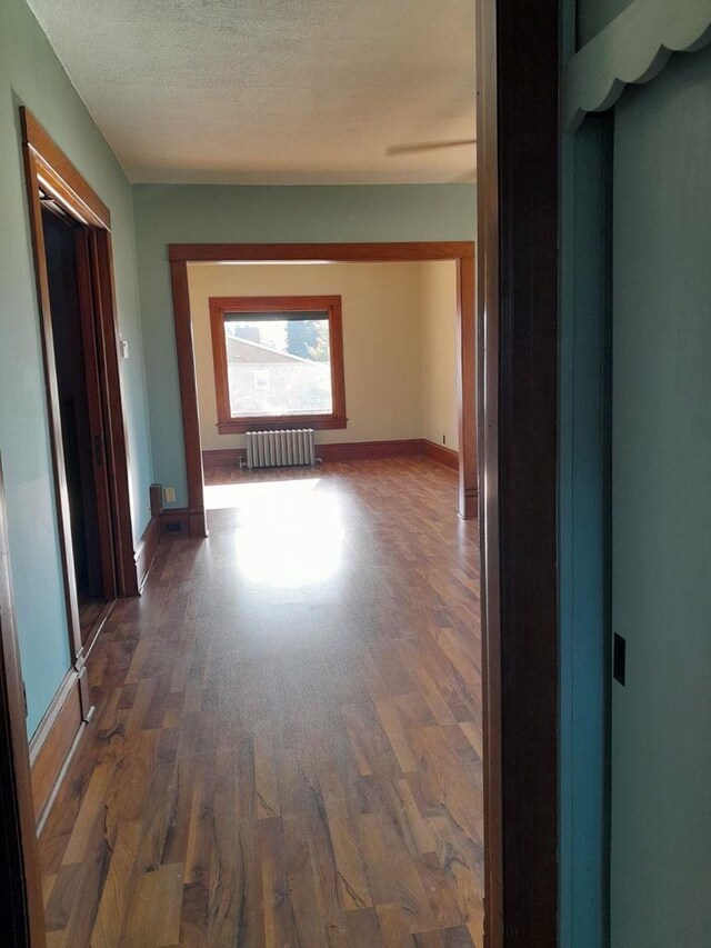 spare room featuring ceiling fan, hardwood / wood-style flooring, and radiator heating unit