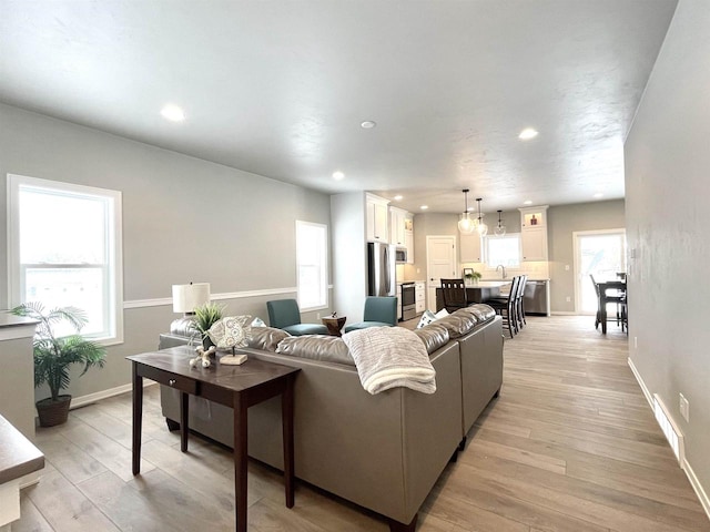 living room with light wood-type flooring, sink, and a chandelier