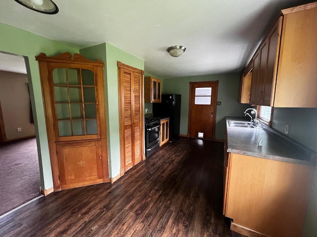 kitchen with sink, black fridge, dark carpet, and stove