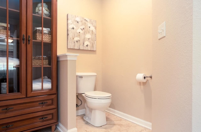 half bathroom featuring toilet, tile patterned flooring, and baseboards