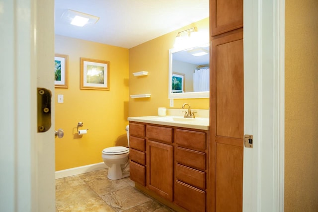 bathroom featuring baseboards, vanity, and toilet