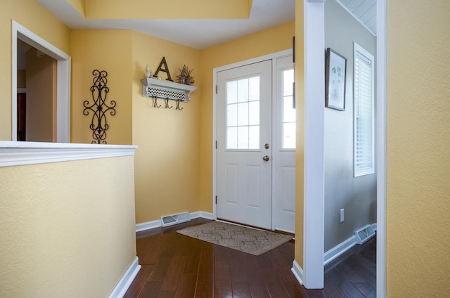 entryway with dark wood-type flooring, visible vents, and baseboards