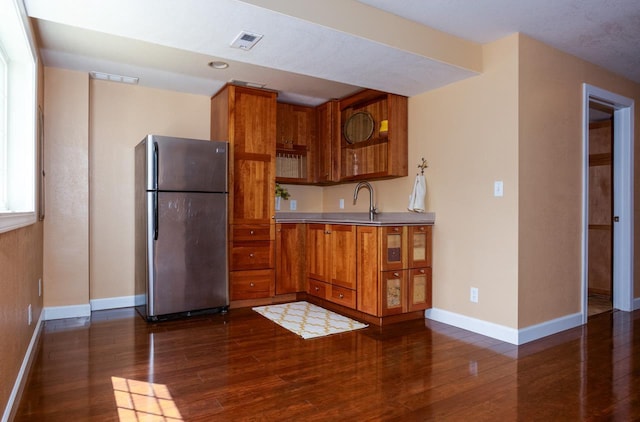 kitchen featuring dark wood-style floors, light countertops, visible vents, brown cabinetry, and freestanding refrigerator