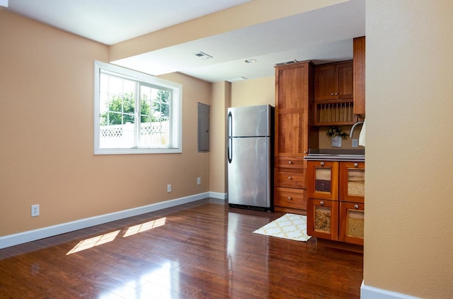 kitchen featuring brown cabinetry, dark wood finished floors, freestanding refrigerator, and baseboards