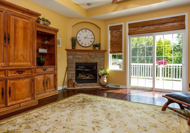 living room featuring dark wood-type flooring, a fireplace, and baseboards